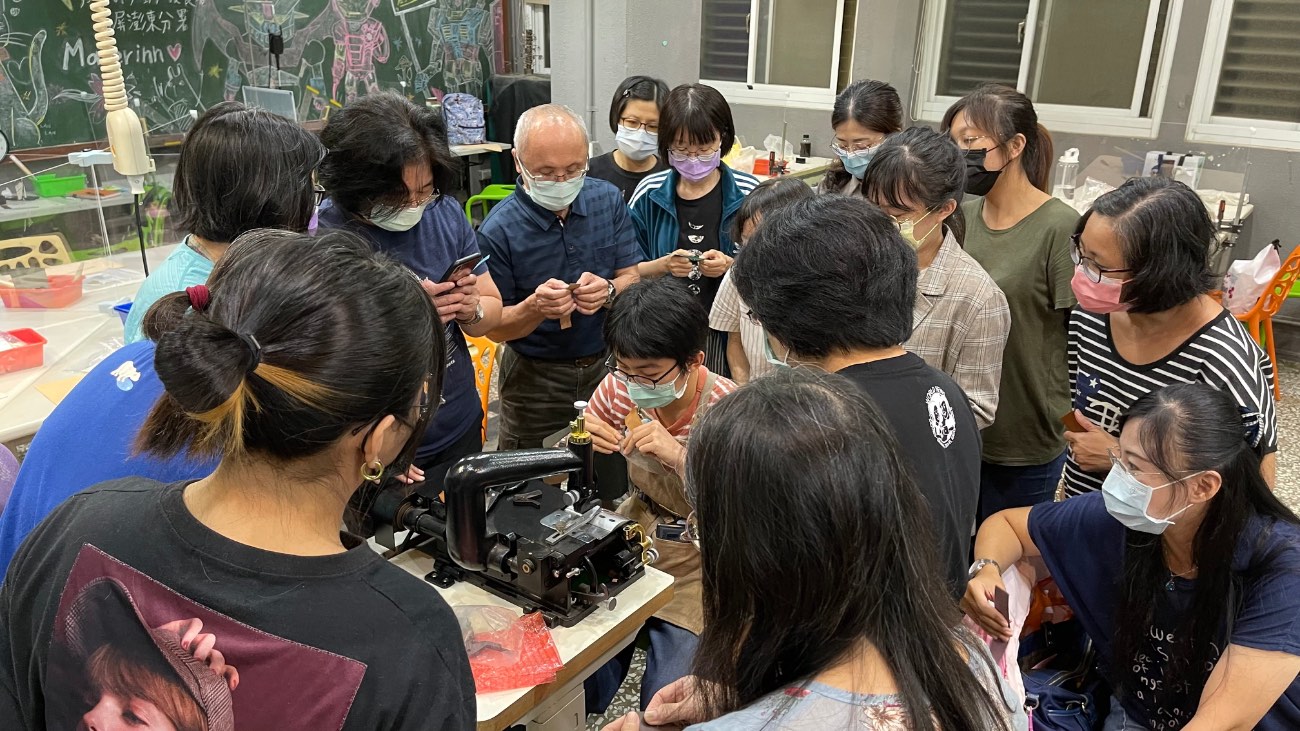 師傅示範縫紉機操作，學員圍繞觀摩